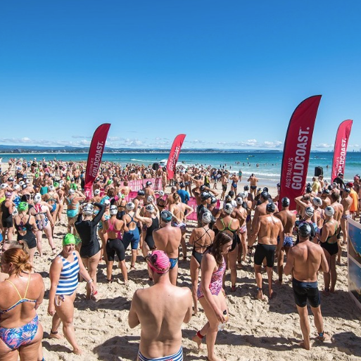 Bronte to Bondi ocean swim — hundreds of swimmers in colourful caps at the start line on a sunny beach